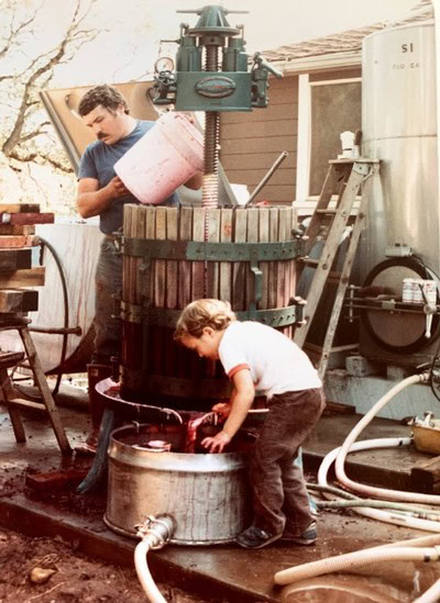 Two workers operating a traditional wine press at Summit Lake Vineyards during harvest.