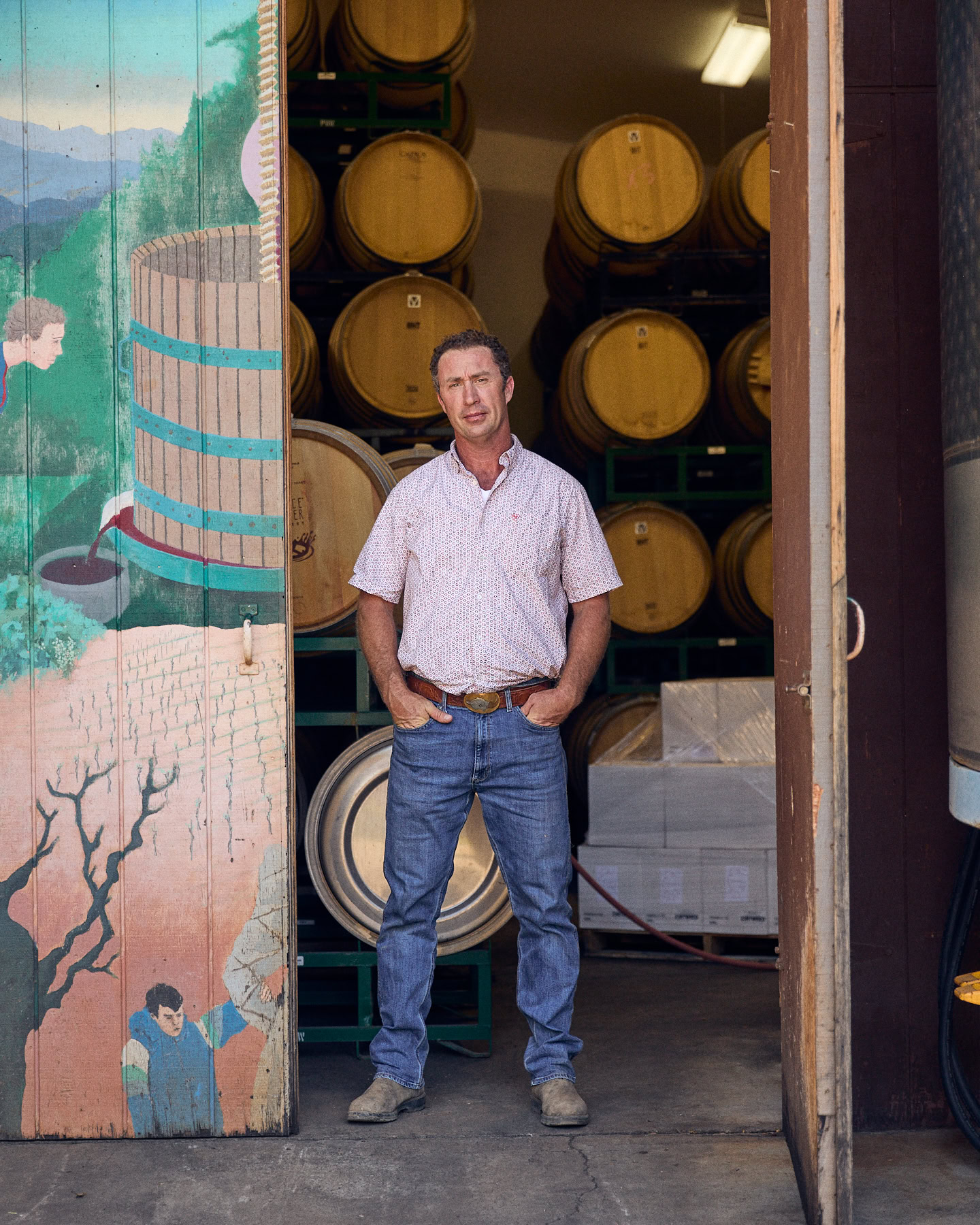 Brian Brakesman standing in front of wine barrels at Summit Lake Vineyards winery.