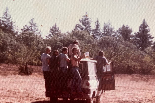 Group of people enjoying a wine tasting at Summit Lake Vineyards, riding on an old van driving through the vineyards.